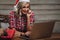 Blonde woman wearing santa hat, working with laptop