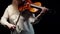 Blonde woman in a white blouse begins to play with bow the violin, standing in the studio on a dark background.