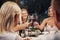 Blonde women with wine glasses. Group of friends in the elegant wear have luxury dinner