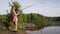 Blonde young girl fisherman is fishing on the forest lake, dragging, caught a fish, holding the fishing rod twists the