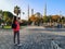 A blonde young tourist woman photographs the Blue Mosque in Istanbul Turkey on a smartphone, view from the back. Travel to