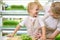 Blonde young woman and a little boy in identical aprons are having fun on a micro-greenery farm