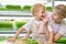 Blonde young woman and a little boy in identical aprons are having fun on a micro-greenery farm