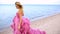 Blonde young woman for long amazing white pink wedding dress on the sea