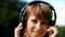 Blonde young woman in park listening to music on headphones