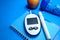 blood glucose meter, notepad and apple on blue background