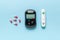 A blood glucose meter, a piercing device and pills for treatment on a blue background. The concept of getting rid of diseases