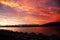 Blood-red dramatic sunset in Gelendzhik Bay. Sea, beach and fungi from the sun in the foreground, the sun sets in the mountains