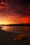 Blood-red dramatic sunset in Gelendzhik Bay. Sea, beach and inverted yellow boat in the foreground, the sun sets in the mountains