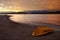 Blood-red dramatic sunset in Gelendzhik Bay. Sea, beach and inverted yellow boat in the foreground, the sun sets in the mountains