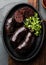 Bloody sausages - chilean preta on iron plate, top view, grey slate background