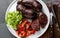 Bloody sausages served on white plate, top view