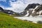 Blooming alpine meadow next to ice of mountain lake