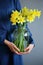 Blooming daffodil in glass jar in woman hands