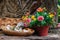 Blooming flowers in pot with wooden candle stand and outdoor decor. Patio design details. Garden in spring.