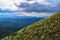 Blooming green diagonal meadow with yellow pink white flowers on hill in the blue Baikal mountains ridge