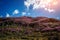 Blooming hill on background of blue sky with light white clouds in the beautiful sunlight. Spring flowers on mountain slopes