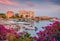 Blooming pink flower on the shore of Kardamyli port with St. John church and Old Customs of Kardamili