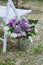 Blooms in Harmony: Lilac Peonies, Giant Onions, and Carnations Adorn a Decorative Bucket, Elevating Outdoor Events and Weddings