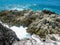 A blowhole among rocks and rough cliffs with blue ocean at the background.