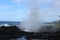 A blowhole spraying water high into the air onto volcanic rock at Waianapanapa State Park, Hana, Maui