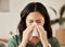 Blowing nose, tissue and woman in a living room with flu, cold and hay fever, crisis or viral infection in her home