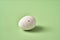 Blown out white Easter egg decorated with wax with drilled holes on a green background