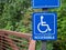 Blue accessible handicap sign hanging on nature hiking path