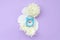 Blue alarm clock and white flowers lies on menstrual pads on pastel lilac background