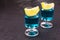 Blue alcoholic cocktail with a slice of lemon on a black background. Copy space.