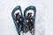 Blue aluminum snowshoes in a snowbank