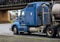 Blue American bonnet rig semi truck with tank semi trailer for transportation of liquids and chemicals running on the road under
