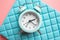 Blue analog metal alarm clock on stylish blue-pink background. Concept of time in pastel colors