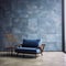 Blue armchair and bench against of concrete tiled wall. Loft interior design of modern living room with stone tiles floor
