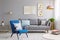 Blue armchair near grey settee in modern living room interior wi