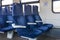Blue armchairs in empty train in row of three, no people in wagon,