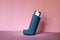Blue asthma inhaler on a pink background