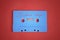 Blue audio cassette tape with christmas songs laying on red paper background.