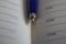 A blue automatic pen lying on the spread of a notebook.