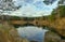 Blue autumn sky with clouds reflected in the pond