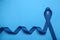 Blue awareness ribbon on color background, top view. Symbol of social and medical issues