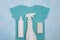 Blue baby bodysuit and different types of stain removers. Dirty clothes. Stubborn stains. Clean linen. Soap, spray bottle. stains