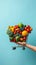 Blue background, hand holds shopping cart filled with fruits and vegetables