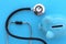 On a blue background lies a stethoscope and a piggy bank.