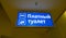 Blue backlit sign. Public WC. Text Translation from Russian: Paid toilet.