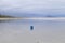 A blue ball, air balloon on a deserted beach, with beige sand and blue mountain background. Cloudy sky in low light. Small waves i