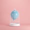 Blue balloon floating in white cage on pastel pink background.