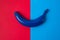 Blue banana on the bright background of red and blue colors. Top view image