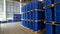 Blue barrel 200 liter chemical drums are stacked on wooden pallets inside the warehouse awaiting delivery. Concept of Chemical