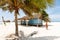 Blue beach house with small veranda, thatched roof standing on beach near ocean